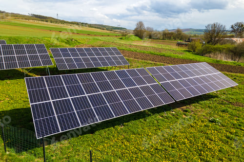 Preview: Aerial view of blue photovoltaic solar panels mounted on backyard ground for producing clean