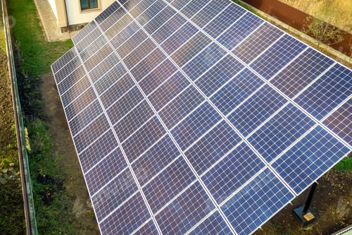 Preview: Aerial view of big blue solar panel installed on ground structure near private house