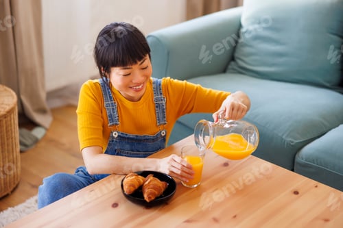 Preview: Woman Pours Orange Juice at Home Indoors