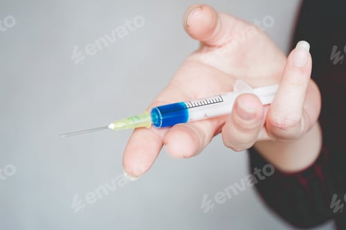 Preview: Womans hand holding a syringe