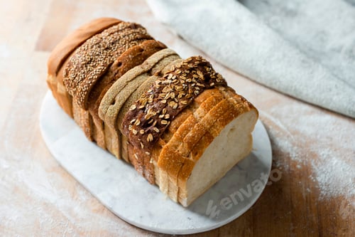 Preview: Sliced loaf made up of variety of white and wholemeal slices on cutting board, high angle view