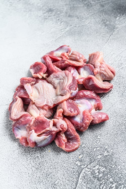Preview: Raw uncooked chicken gizzards, stomach. Gray background. Top view