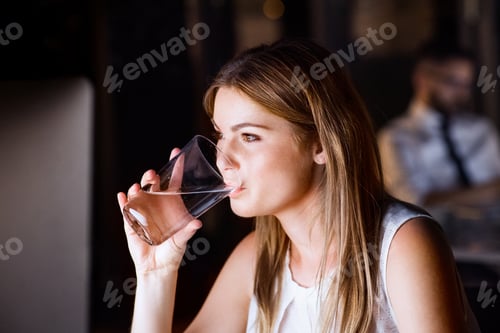 Preview: Businesswoman drinking water in office at night.