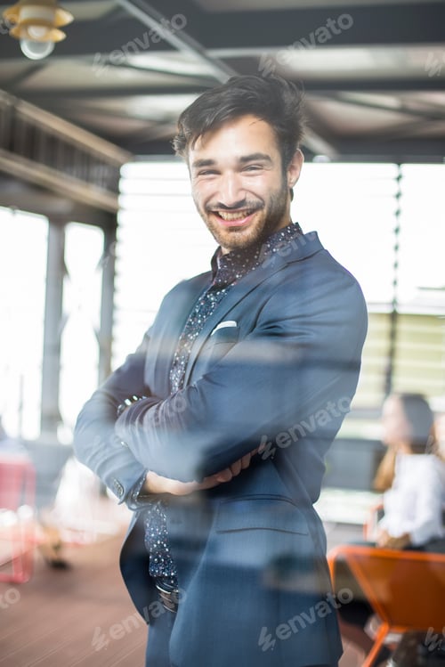 Preview: Portrait of happy businessman with arms crossed standing in office