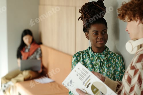 Preview: Smiling Young Adult Black Woman Collaborating with Colleagues in Coworking Space