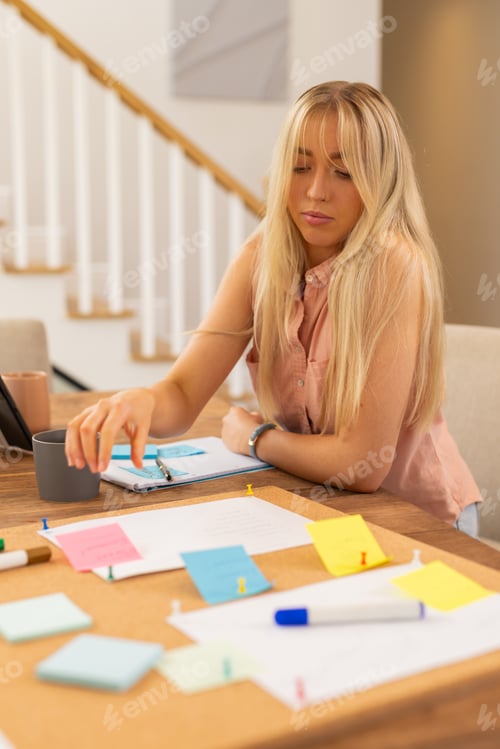 Preview: Organizing notes on corkboard, woman working at home with coffee mug