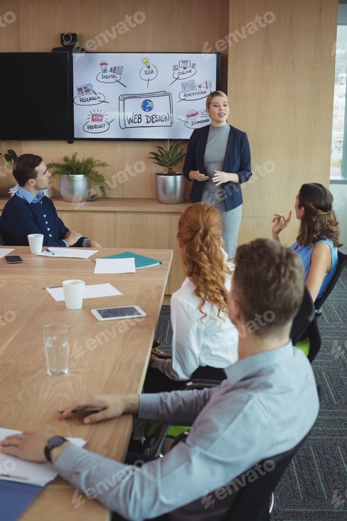 Preview: Young businesswoman discussing with colleagues during meeting