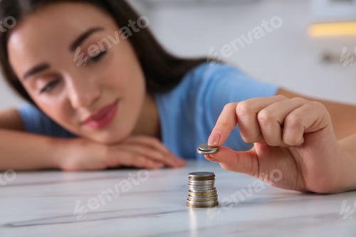 Preview: Young woman stacking coins at table, focus on hand. Money savings