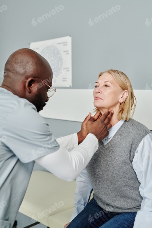 Preview: African American male endocrinologist checking thyroid of mature female patient