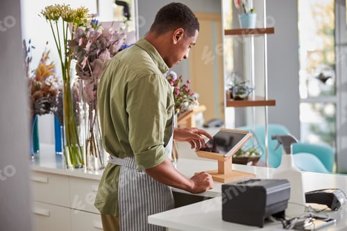 Preview: Male shop assistant working in flower shop