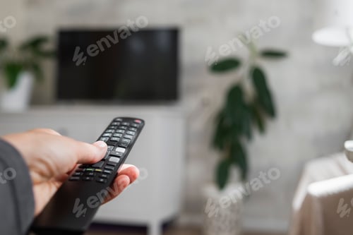 Preview: Hand with TV remote control in living room