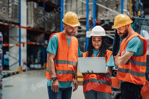 Preview: Multiracial warehouse team strategizing around a laptop for success