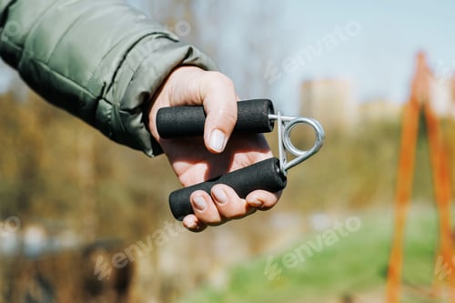 Preview: Close-up of woman exercising her hand using an expander outdoors