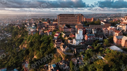 Preview: Aerial view of Antananarivo at sunset showcasing vibrant urban life and lush greenery on a hillside