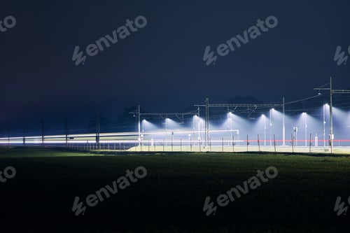 Preview: Light trail of train. Traffic on electrified railroad track at night.