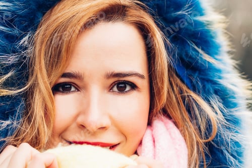Preview: Cara de una mujer adulta joven rubia envuelta en un sombrero de invierno y una bufanda.