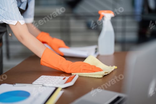 Preview: Female office cleaner wiping desk with cleaning supplies and documents. Concept of workspace