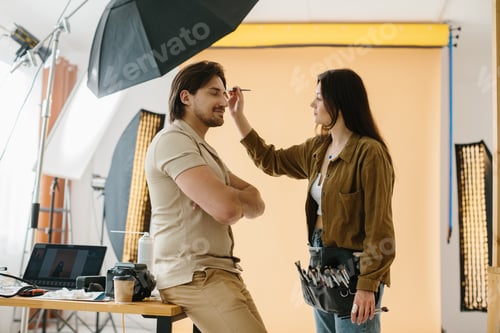 Vista previa: Make-up artist working during a photo session while preparing the look for the model