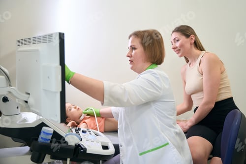 Preview: Doctor adjusting ultrasound screen with mother observing