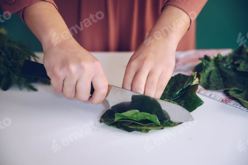 Preview: Woman cutting spinach on the marble at her kitchen