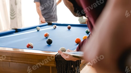Preview: Anonymous man playing pool with friends in game room at home