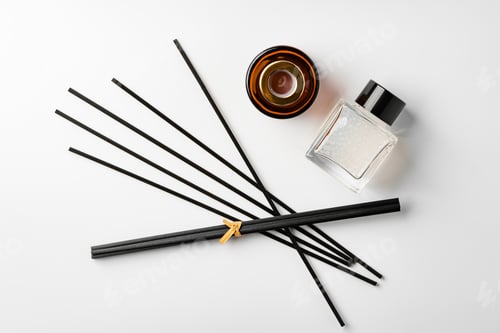 Preview: A minimalist display of essential oil and black diffuser sticks on a clean white background