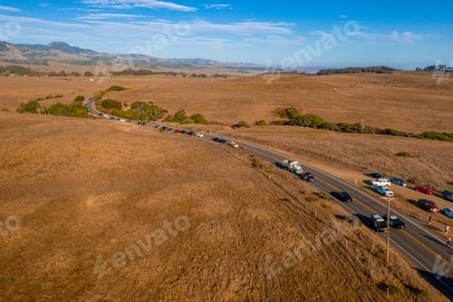 Preview: Aerial shot of cars on the road surrounded by fields under a blue sky