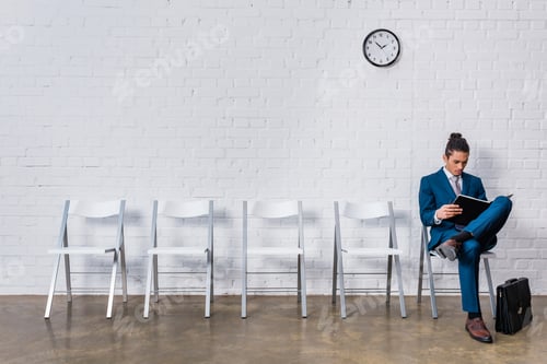 Preview: Man reading papers while sitting on chair