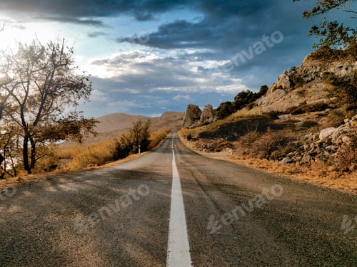 Preview: Dramatic sky and bright sunlight over Empty open road through exotic landscape.