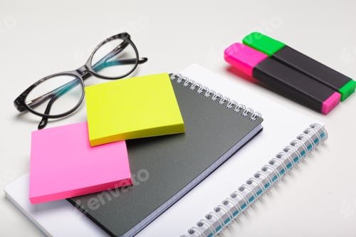 Preview: Sticky notes with markers, colored pens, paper clips laying on a table