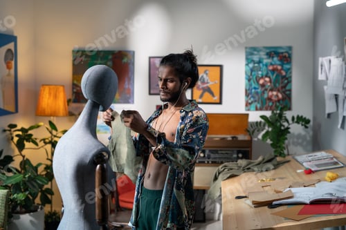 Preview: Young modern tailor trying paper pattern of new apparel on mannequin