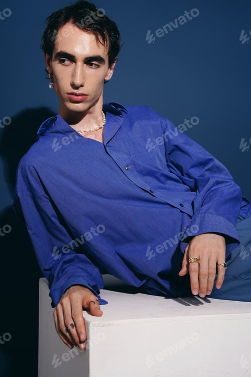 Preview: Stylish man poses confidently in vibrant blue outfit against deep blue backdrop