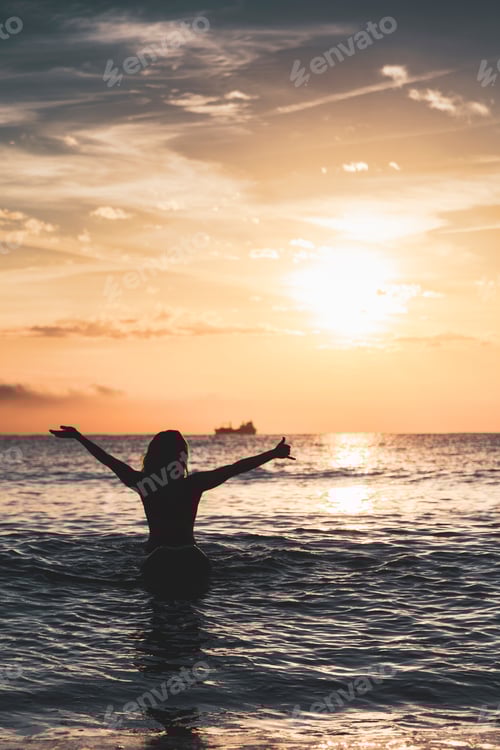 Preview: Silhouette of woman sitting on surfboard on beach