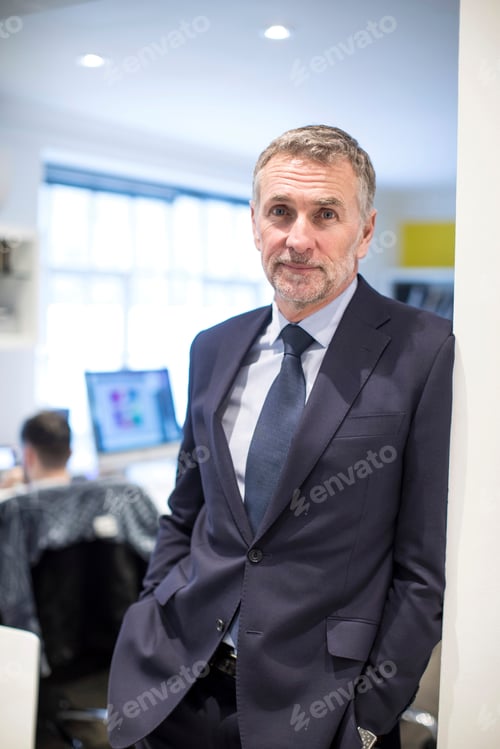 Preview: Portrait of businessman in office leaning against wall