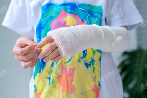 Preview: Child doing massage on fingers of broken hand wrapped in white plaster bandage.