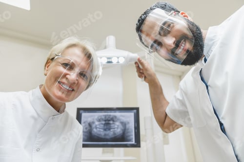 Preview: Dentists looking checking up patient`s mouth cavity, curing teeth tooth in protective masks.
