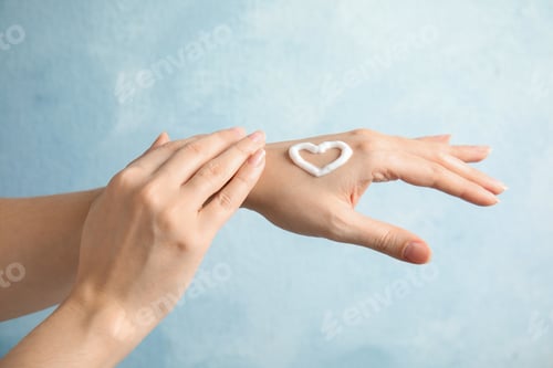 Preview: Woman applying hand cream on light background, closeup