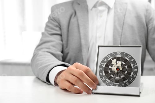 Preview: Man with darts at table. Business trainer concept