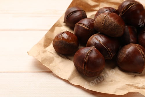 Preview: Roasted edible sweet chestnuts on wooden table, space for text
