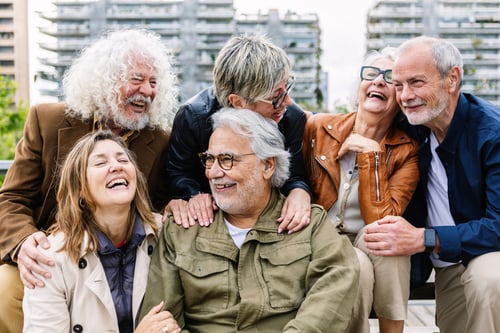 Preview: Happy group of senior people laughing while sitting together outdoors