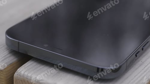 Preview: Close up of a part of a black screen of a new smartphone on wooden bench background. Action. New