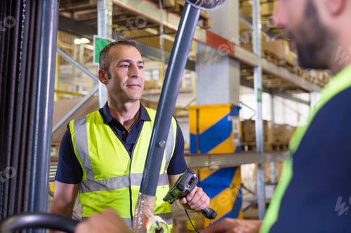 Preview: Supervisor instructing male forklift truck driver in distribution warehouse