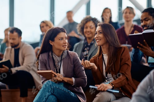 Preview: Happy female entrepreneurs talking while attending business seminar at convention center.