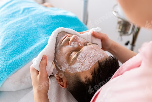 Preview: Beautician doing face treatment in beauty salon to man.