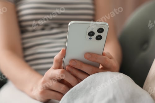 Preview: Woman using modern smartphone on sofa at home, closeup