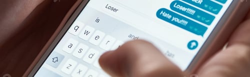 Preview: panoramic shot of abuser typing offensive messages while using smartphone, illustrative editorial