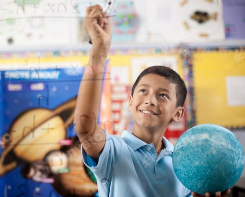 Preview: A girl writing with a pen on a board of equations and formulae in the classroom.