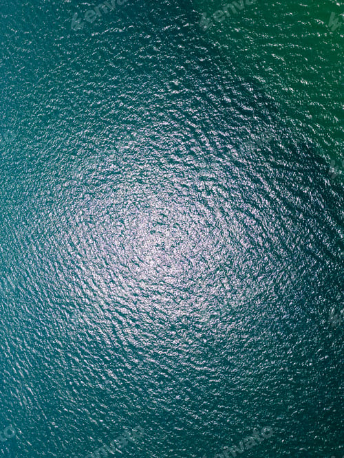 Preview: Aerial view of sun reflections on the surface of rippling turquoise sea water.