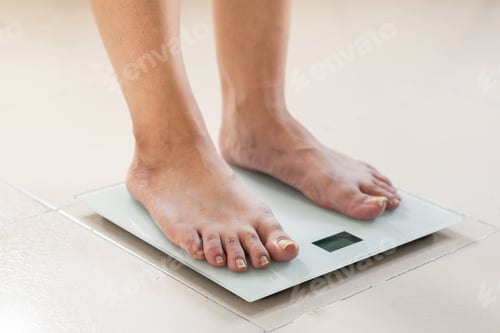 Preview: detail of a woman's feet, standing on a scale, calculating her body mass. taking care of her health