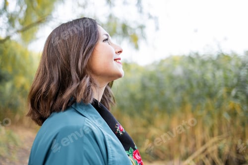 Preview: Autumn vibes. Beautiful young relaxed woman in blue coat enjoying nature breathing fresh air meditat